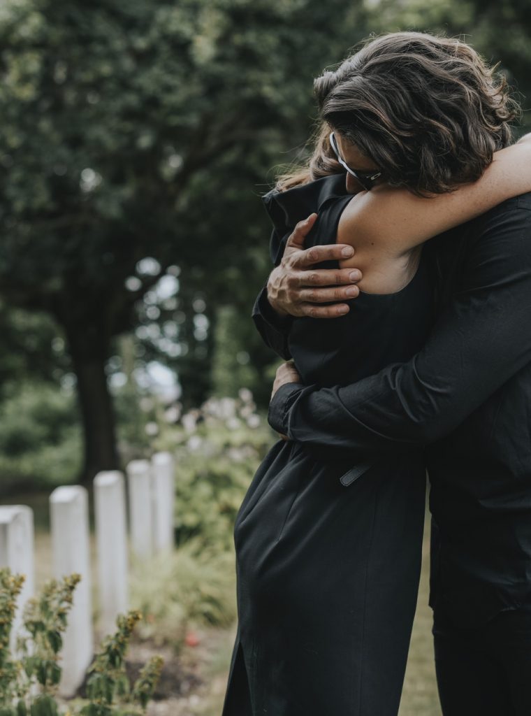 husband-trying-to-comfort-his-wife-at-a-graveyard.jpg husband-trying-to-comfort-his-wife-at-a-graveyard.jpg
